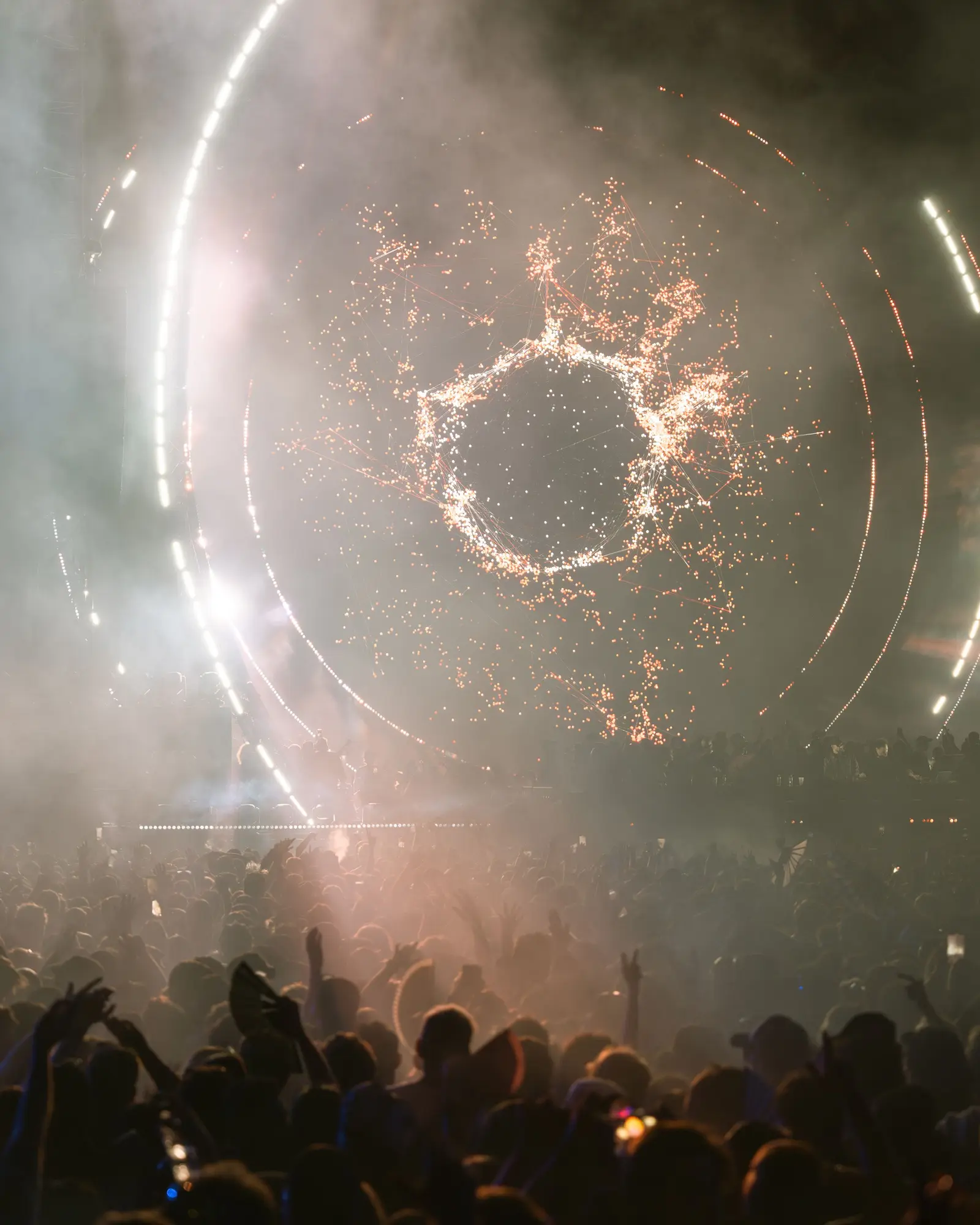 Night-time music festival crowd facing a lit main stage.