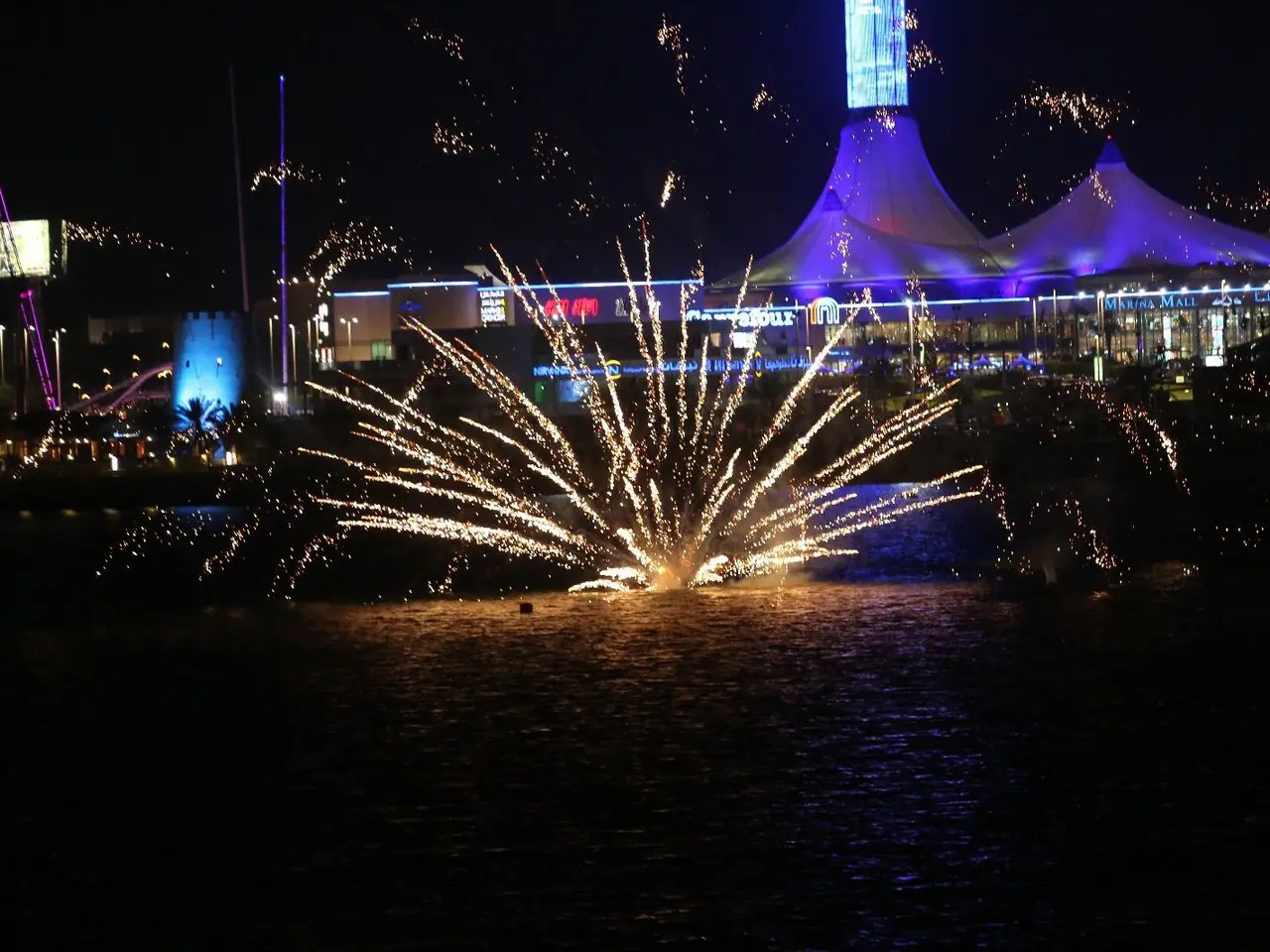 Night festival performance with sweeping light and sparkling effects above the crowd.