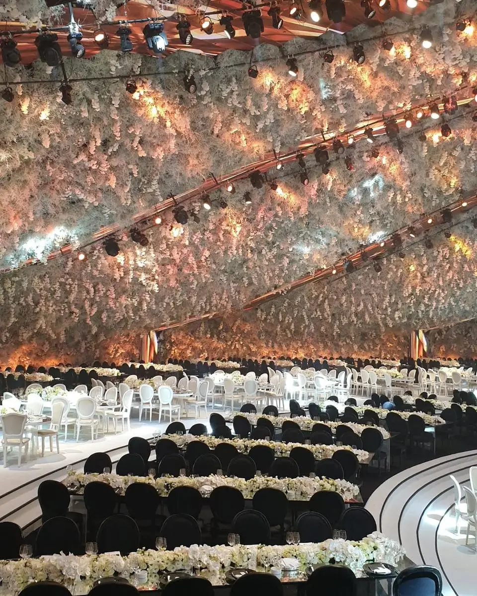 Large event venue prepared beneath a dense suspended floral canopy with guest seating ready.